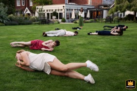 Wedding guests laughing and enjoying themselves as they roll around on the lush green grass at a beautiful wedding at The Farmhouse at Redcoats in Hitchin, Hertfordshire.